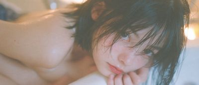 Woman curled in dry bathtub against vivid purple void