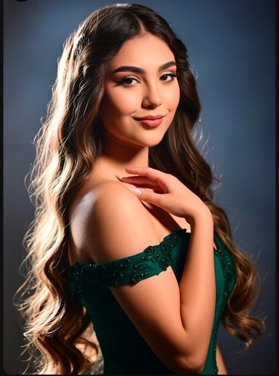 A brunette in an emerald gown gazes warmly under dramatic studio lights