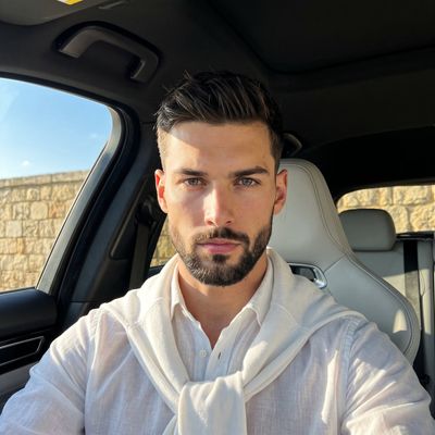 Confident man in white shirt sits inside luxury car under golden sunlight