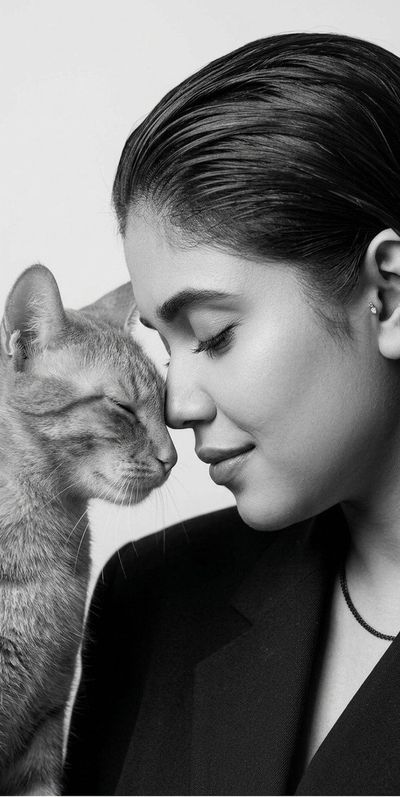 A woman touches foreheads with a black cat in monochrome studio