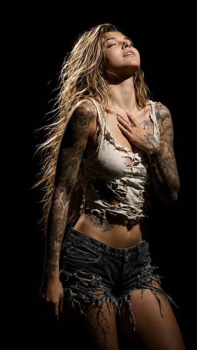Tattooed woman in spotlight arches back with eyes closed