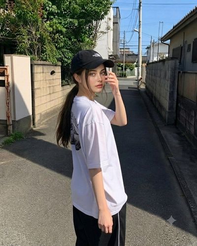 Young woman in cap looks back in a sunny Japanese alley