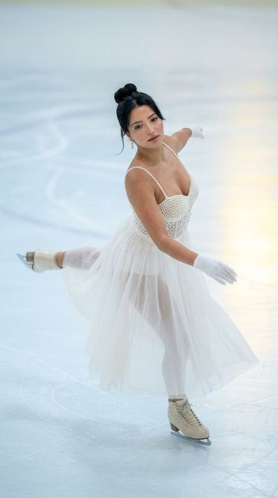 A figure skater in pearl bodice glides on icy rink