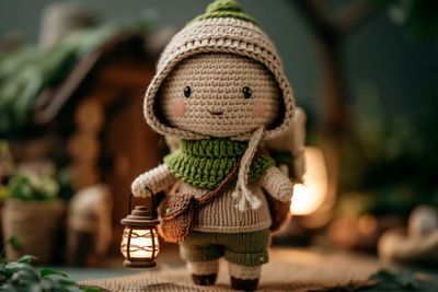 A crochet fox doll wears a warm scarf in a snowy forest