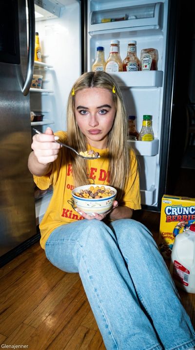 A playful girl steals snacks from the fridge at midnight