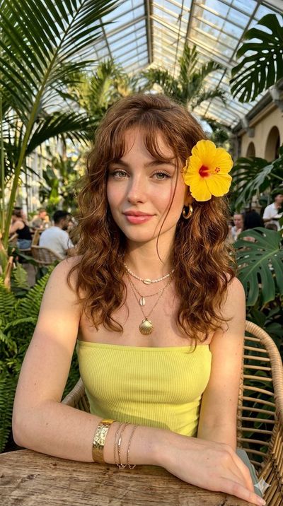 Young woman with red hair and yellow flower gazes in tropical cafe