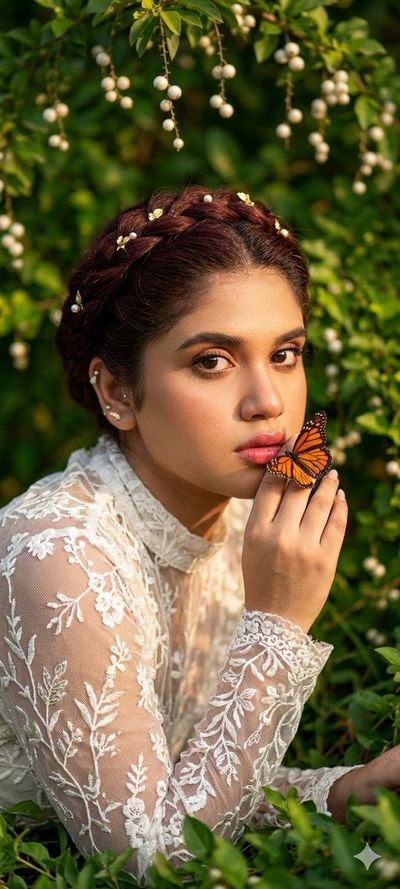 A woman whispers secrets to a butterfly resting on her finger