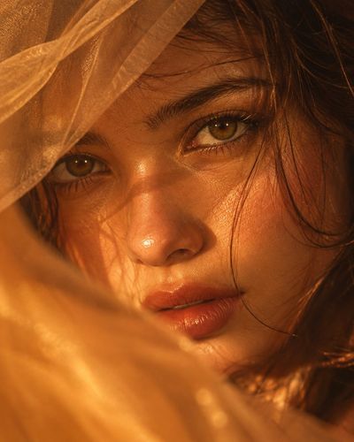 Amber eyes pierce through golden fabric in intimate portrait