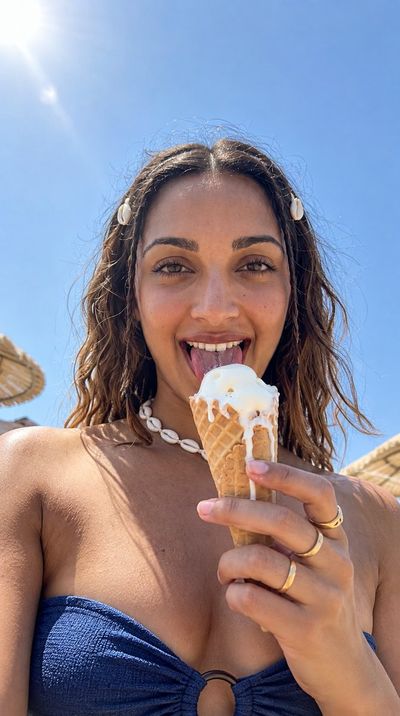 Joyful woman licks melting vanilla cone on sunny beach