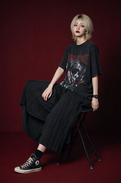 Young woman in gothic streetwear poses with melancholic gaze on stool