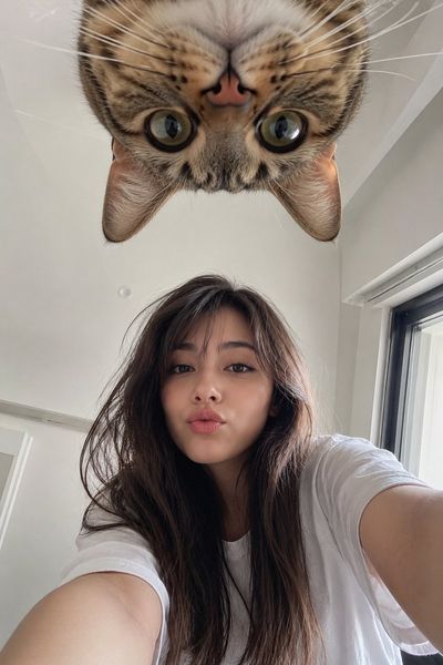 Japanese woman takes playful selfie with upside-down cat above