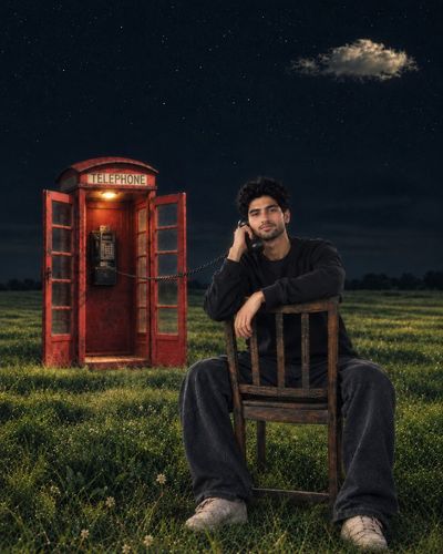 Lonely man holds vintage phone receiver under starry night sky