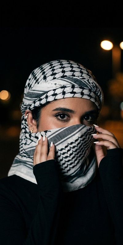 A woman's eyes reveal hidden stories beneath a dark scarf