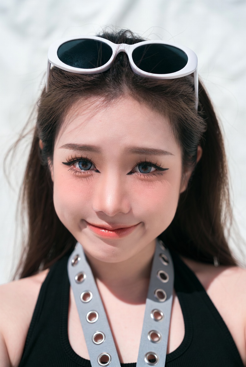 Young woman with sunglasses on head smiles playfully in black top