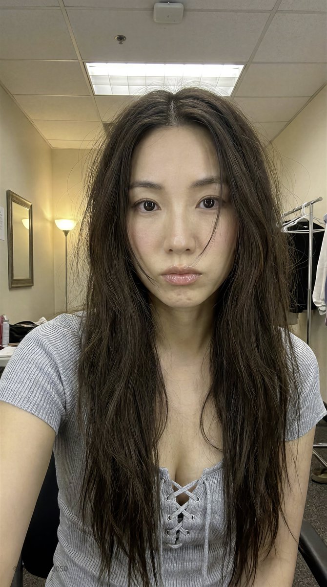 East Asian woman in dressing room with warm lamp glow