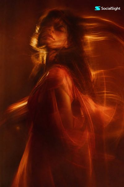A woman's blurred figure moves through warm amber light trails