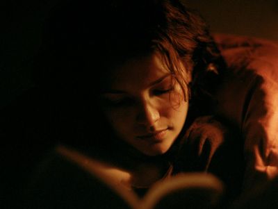 A woman's face lit by candlelight in a dark room