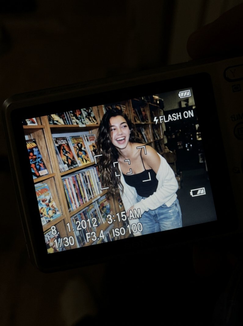 A young woman laughs in a cozy comic book store at night.