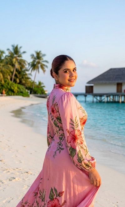 A blonde woman in a floral dress enjoys golden hour on a tropical beach.