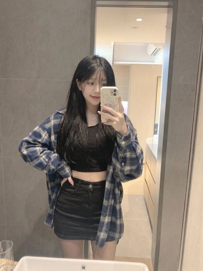 Young girl in plaid flannel takes a playful mirror selfie