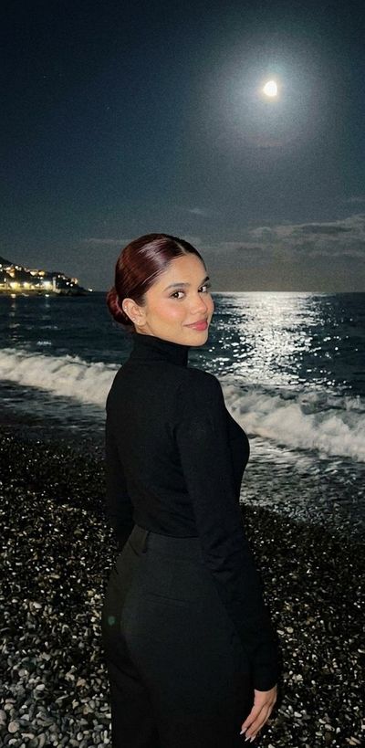 A woman in a zebra top gazes back under a full moon on the beach