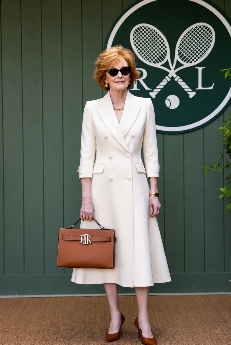 Elegant woman in cream coat dress holds brown leather handbag