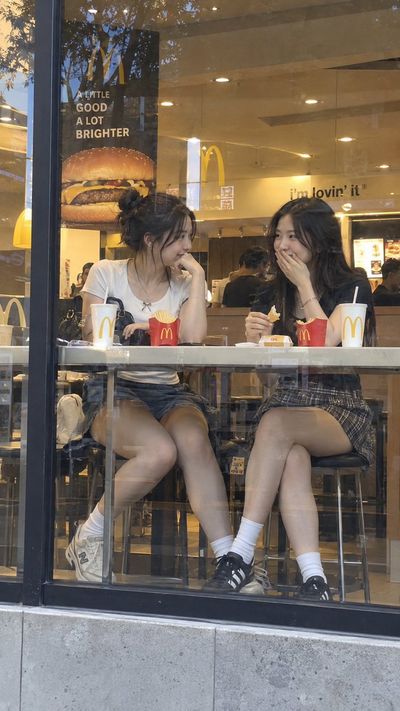 Two Women Chat Through Glass at a Warm McDonald's Window