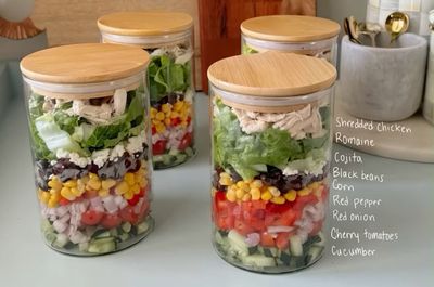 Layered Mexican chicken salad jars glow on a bright kitchen counter