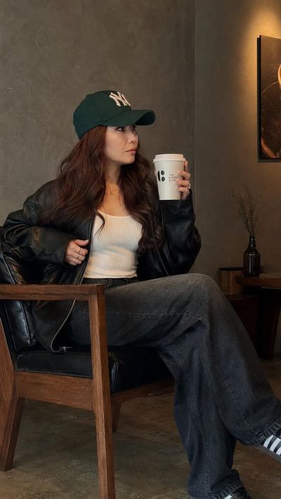 A woman in a green cap sits calmly with coffee in a minimalist café