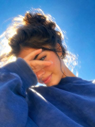 Young woman with glowing skin smiles beneath a deep blue sky