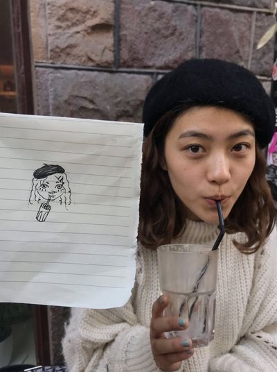 Woman in black beret sips iced drink at outdoor café
