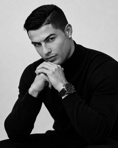 Athletic man in black turtleneck poses for dramatic monochrome portrait.