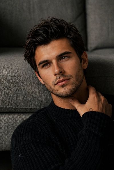 A handsome man with stubble gazes thoughtfully by the window