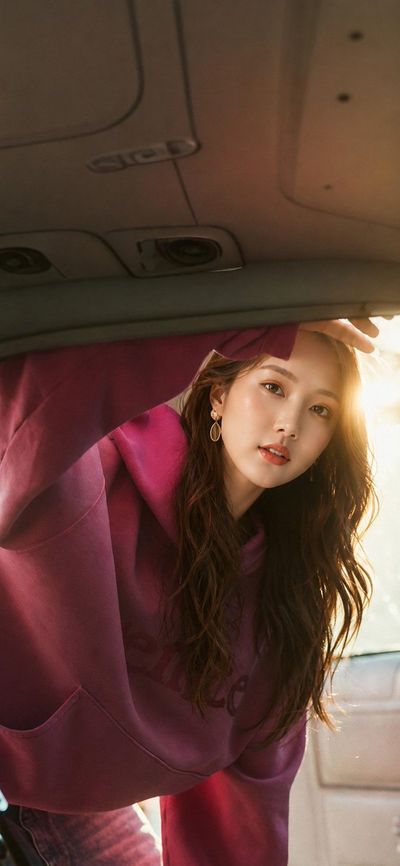 Woman leans into car trunk as golden sunlight streams through