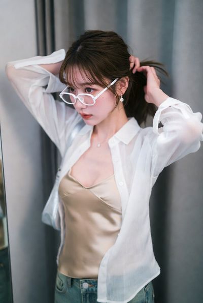 Japanese model lifts hair in fitting room under high-key light