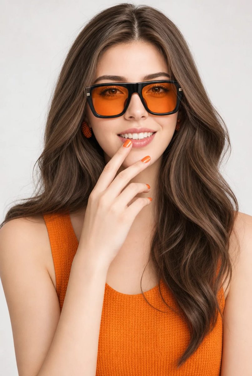 A woman in orange sunglasses smiles playfully in studio light