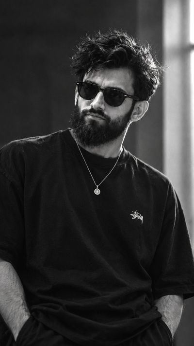 Monochrome portrait captures brooding man with thick beard indoors