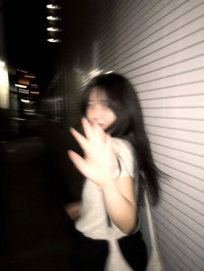 A woman on a Tokyo sidewalk turns back with a shy smile.
