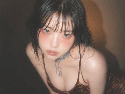 A young woman in velvet top gazes upward with soft flash