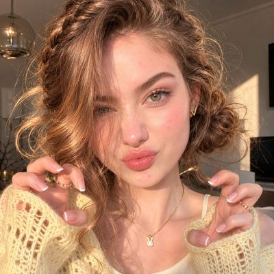 A woman with acne scars models glowing skin and playful pose.