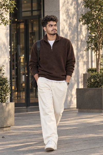 Cinematic full-body portrait of man walking outside modern luxury building