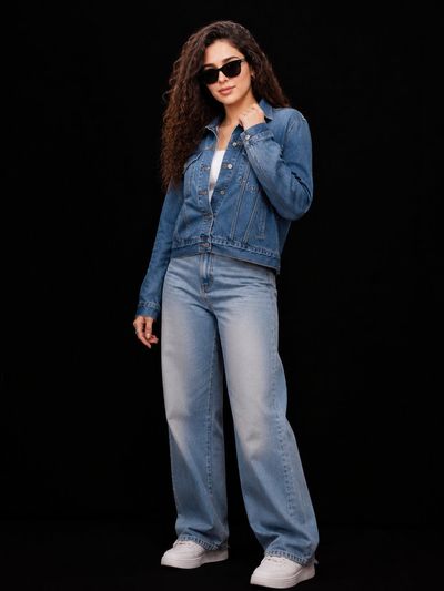 A confident woman in denim jacket poses under cinematic studio lights