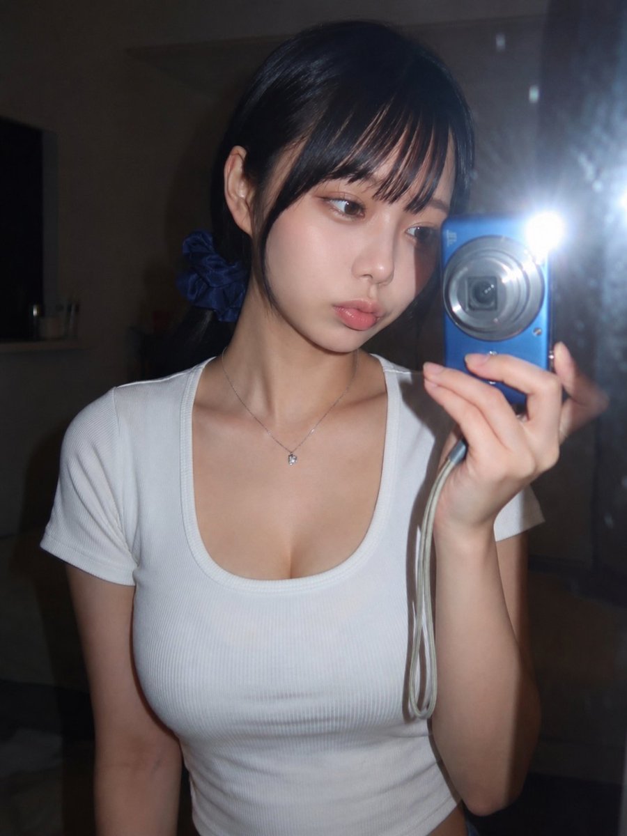 Young woman captures a mirror selfie with bright camera flash
