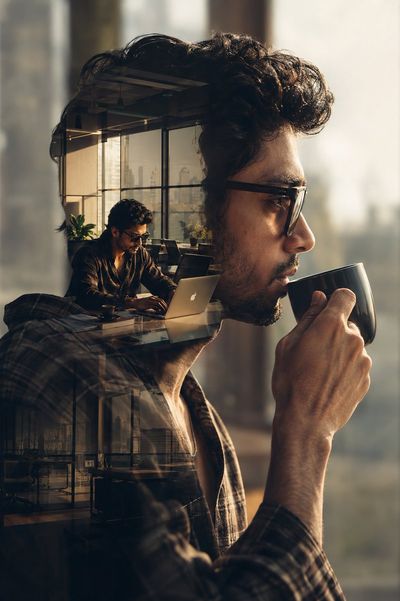 Thoughtful man with coffee blends with sunlit office interior