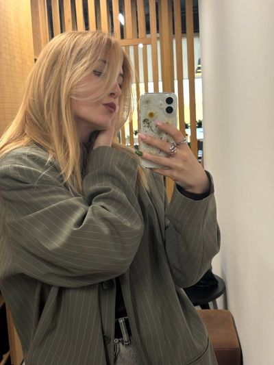 Blonde woman in oversized blazer poses with floral phone case