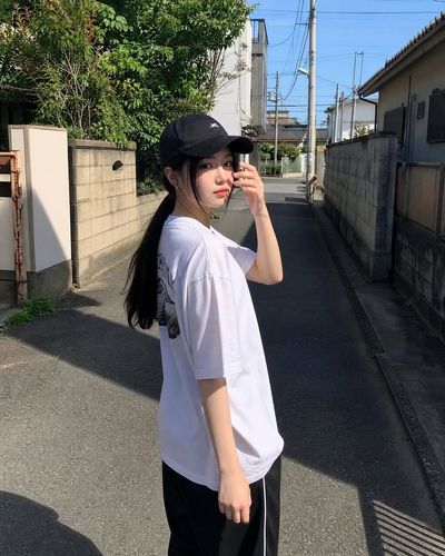 Young woman in baseball cap walks through sunny alleyway