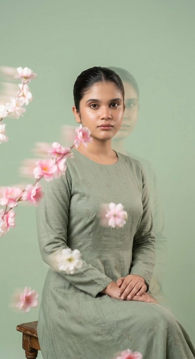 A young woman with serene expression drifts among sage flowers