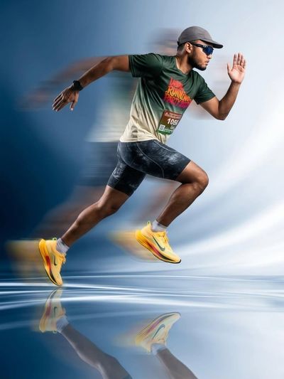 Male athlete sprints mid-air with motion blur on blue background
