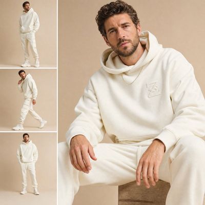 A bearded man in cream white outfit sits casually in studio