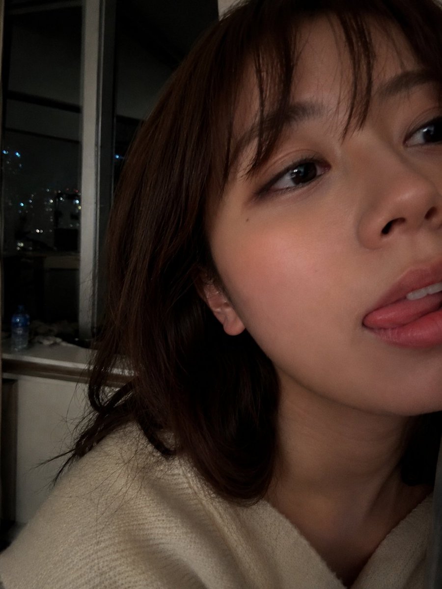 Young woman with dark eyes takes a cozy night selfie indoors
